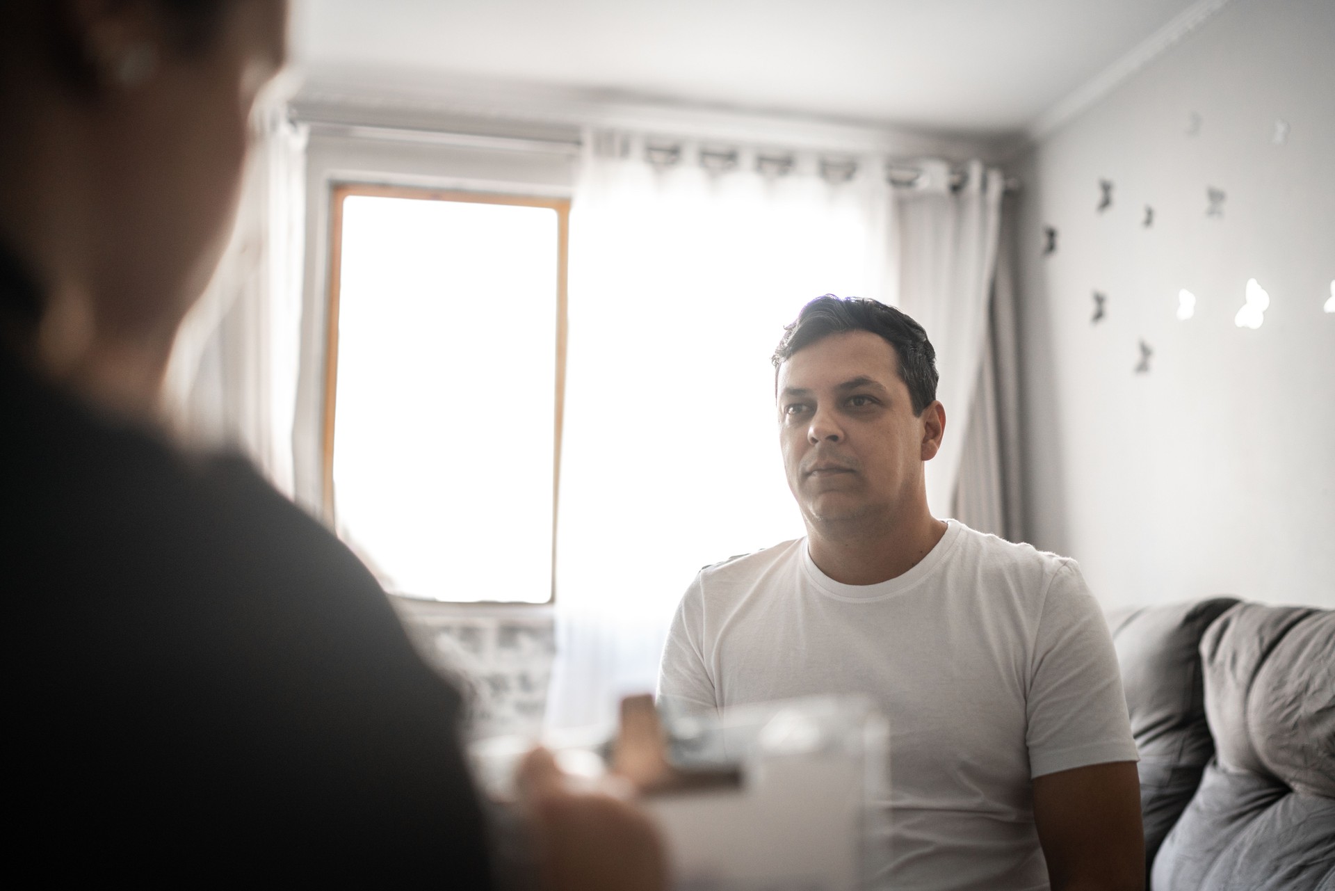 Woman counselor listens compassionately to male client at home